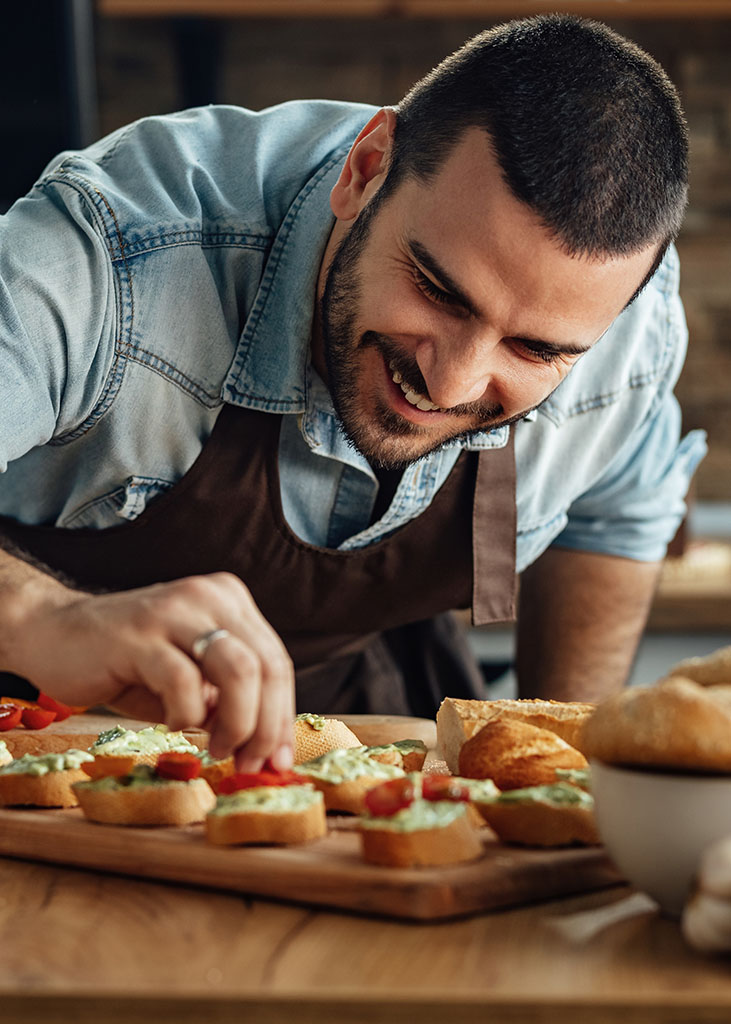 Happy man enjoying in preparing a healthy appetizer in the kitch